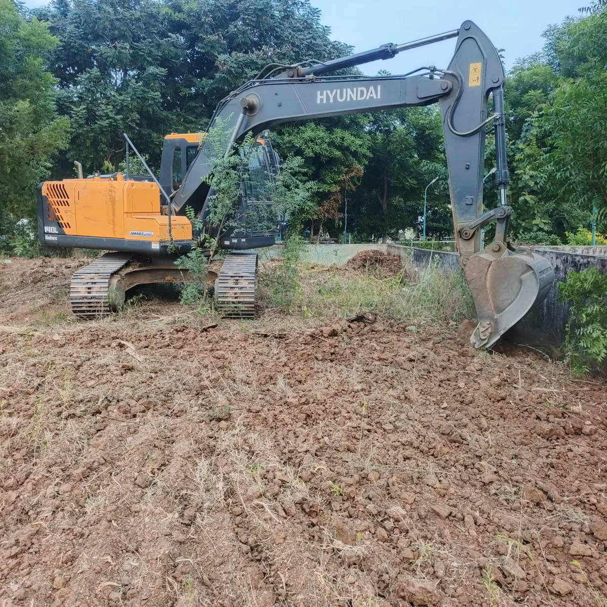 Excavator levelling the ground beside the boundary wall